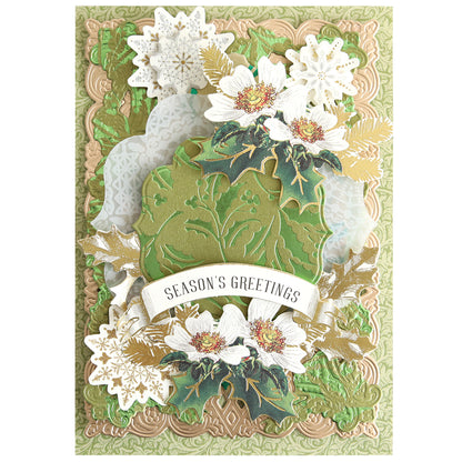 A decorative holiday card featuring the Gilded Christmas Holly Hot Foil Plate, with elegant embossed green and gold patterns, white flowers, snowflakes, and a central banner that reads "Season's Greetings," perfect for creating stunning foiled backgrounds with a sophisticated Christmas holly design.