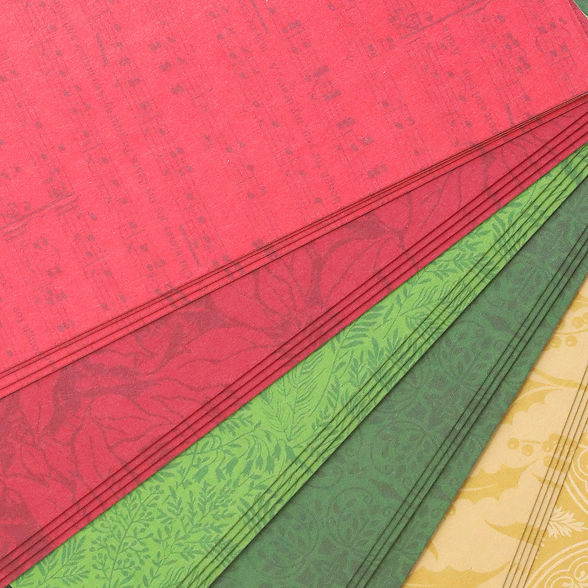 A stack of Holiday Color Drenched Cardstock sheets in vibrant red, green, and yellow hues features an array of unique floral and patterned designs. Each double-sided cardstock sheet is arranged diagonally with partial overlap, making them ideal for Christmas card making and other festive paper crafting projects.