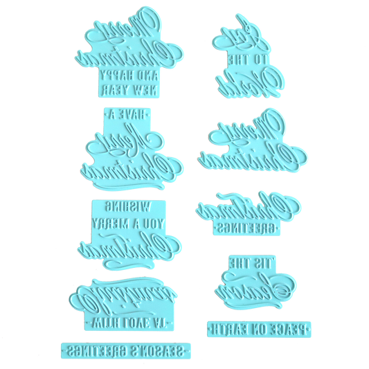 Eight blue plastic embossers with reversed festive phrases, such as "Happy New Year," "Season's Greetings," and "Wishing You A Merry Christmas," are arranged on a white background. These embossers are ideal for adding charming holiday greetings to your foiled Christmas cards or for use with the Gilded Small Christmas Sentiments Hot Foil Plates.