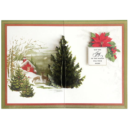 The Folded Christmas Tree Card Making Kit features a pop-up card with a 3D Christmas tree, a snowy cabin, deer, and the message “May the joy of the season fill your home” beside a poinsettia illustration—an enchanting addition to your collection of handmade Christmas cards.
