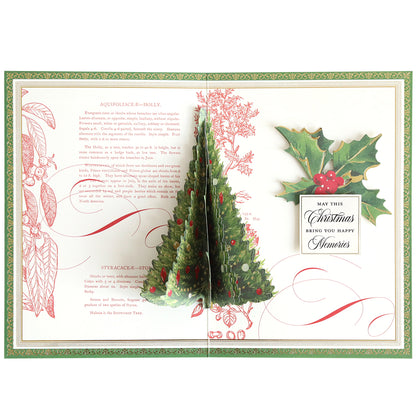 Create a unique card with the Folded Christmas Tree Card Making Kit, which includes materials to craft a pop-up card featuring a 3D Christmas tree, festive holly illustrations, and a heartfelt greeting that says, "May this Christmas bring you happy memories," along with decorative holly text in the background. Ideal for anyone who loves folded Christmas tree cards or enjoys making their own handmade holiday greetings.