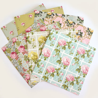 The Rose Cardstock Collection features eight double-sided pastel sheets with floral and rose patterns, beautifully displayed in a fan shape—ideal for scrapbooking and paper crafts.