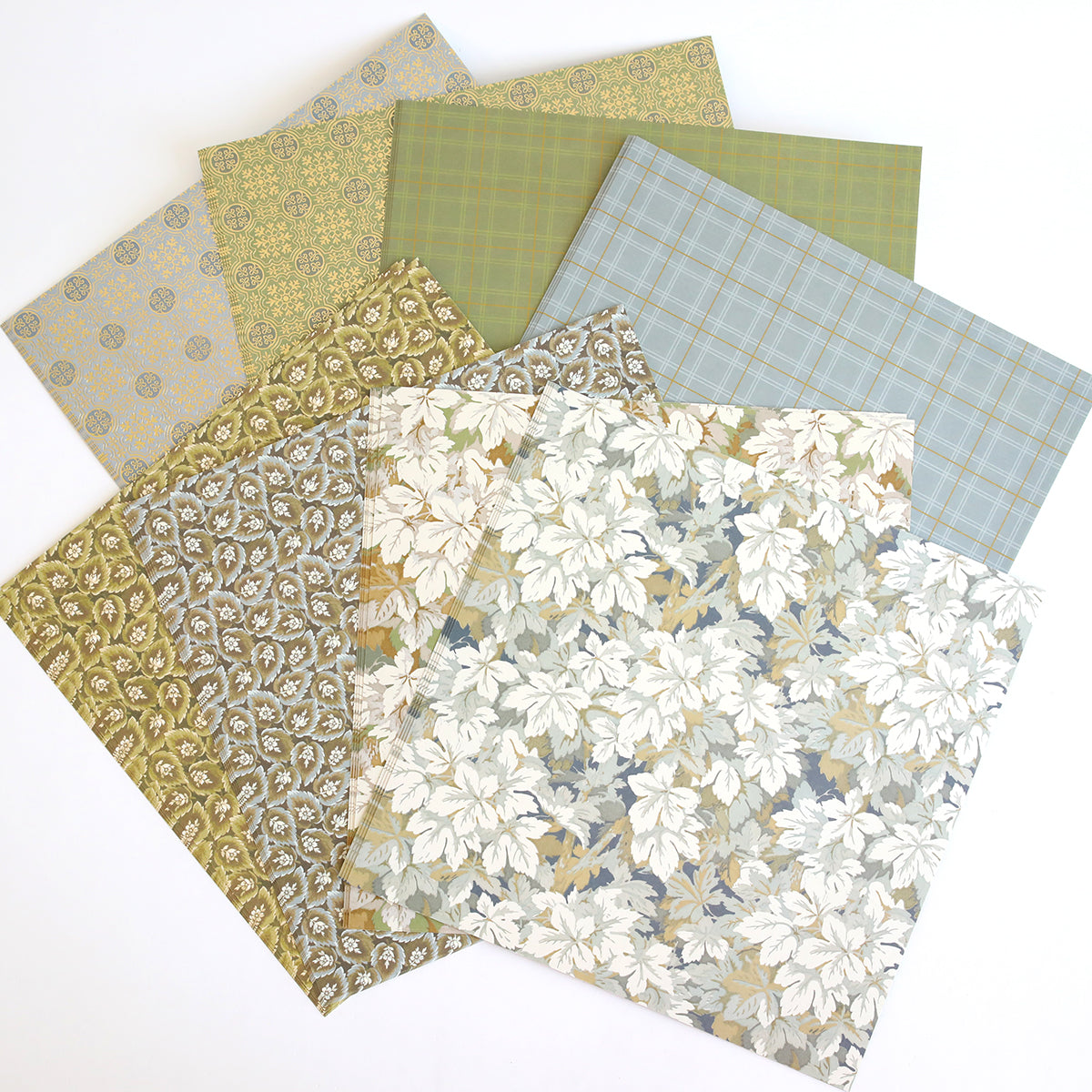 Seven square sheets from the Jack Double Sided Cardstock and Embellishments set are fanned out on a white background, showcasing floral and geometric designs in green, beige, and blue tones—ideal for bringing a stylish flair to your scrapbook pages or coordinating with matching die cut embellishments.