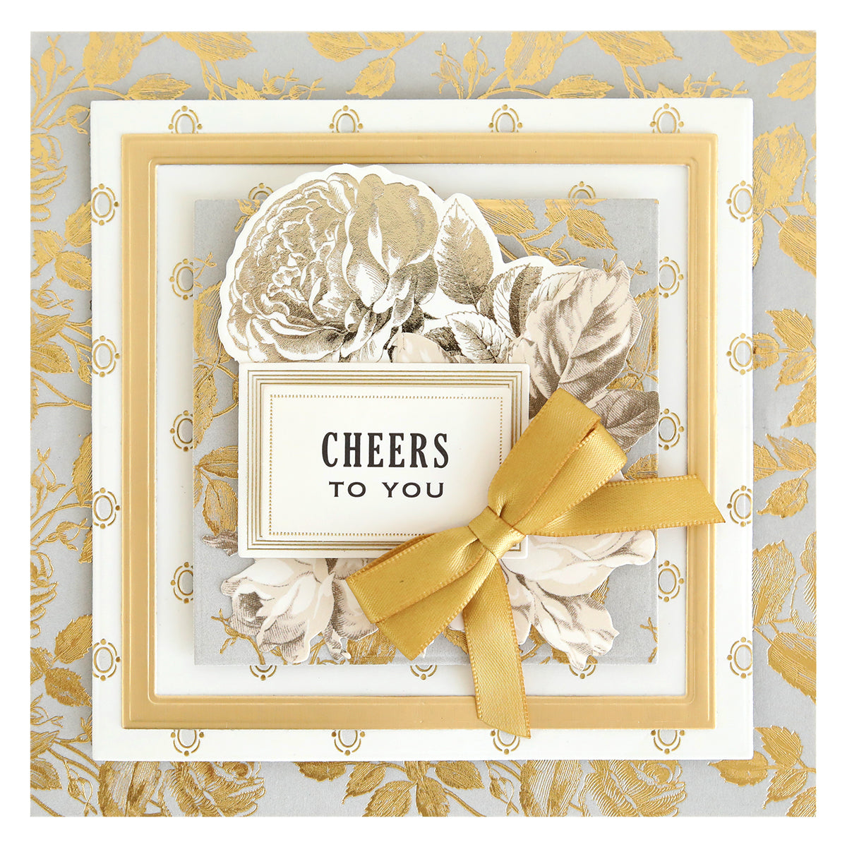 A greeting card made with Concentric Square Dies, featuring layered gold and white frames, a gold ribbon bow, floral illustrations, and "CHEERS TO YOU" in the center.