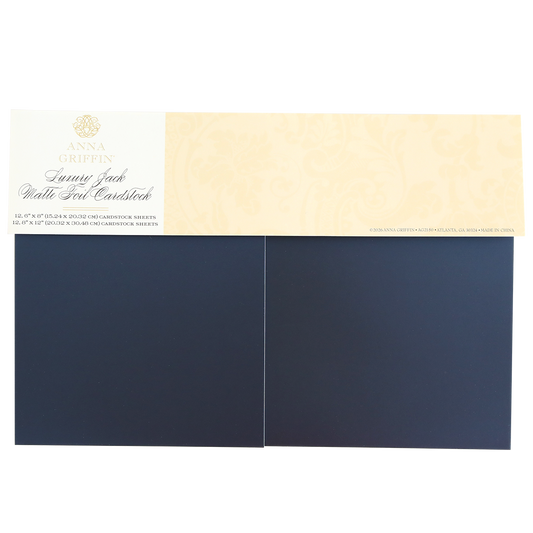 A pack of Luxury Jack Matte Foil Cardstock includes two sheets of dark blue matte foil cardstock with a beige label on top—ideal for handmade cards and scrapbooking projects.