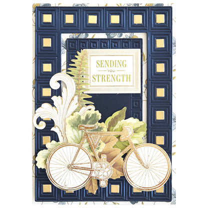 Greeting card from the Celebration Foil Cardstock Collection, adorned with a gold-trimmed bicycle, leaves, and fern, featuring a raised blue and gold border on navy matte foil cardstock and the message “Sending You Strength” in the center—an ideal addition to thoughtful paper crafts.