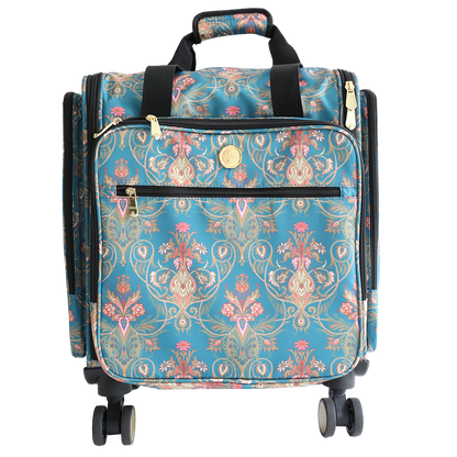 The Jasmine Rolling Craft Luggage features a teal floral and gold pattern, black handles, zippered pockets, and four swivel wheels, photographed against a white background.