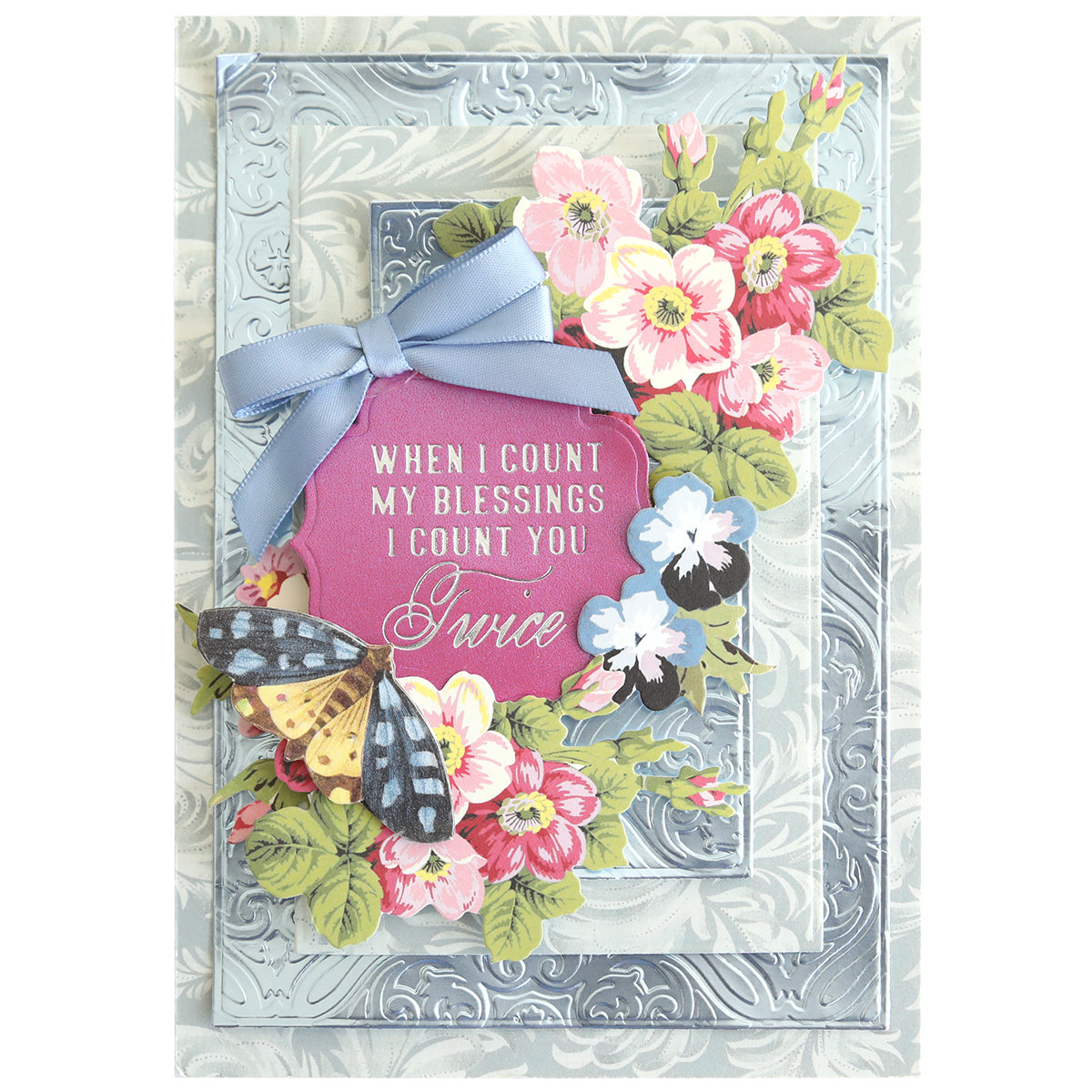 Greeting card featuring floral decorations, a blue ribbon, and a butterfly. Beautifully crafted with the Gilded Small Sentiments Foil Plates Bundle, this card showcases elegant, intricate hot foil techniques for a refined finish. The sentiment on the card reads: "When I count my blessings I count you twice.