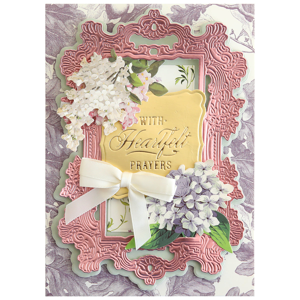 A decorative handmade card adorned with a pink ornate border, white bow, flower illustrations, and the heartfelt message "With Heartfelt Prayers" at its center. Crafted using the Gilded Small Blessings Sentiment Foil Plates, this card features delicate hot foiled details that beautifully convey your warmest sentiments for any heartfelt occasion.