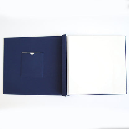 The Jack Navy Post Bound Scrapbook Album is open and empty, showing blank white pages and a small inside cover pocket—ideal for crafting personalized scrapbook layouts, seen from above.