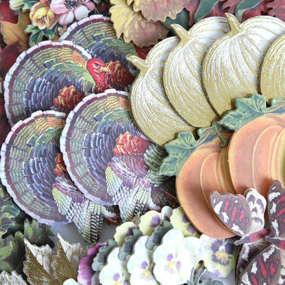 Fall Ephemera Embellishments featuring an assortment of autumn-themed paper cutouts—including turkeys, pumpkins, leaves, flowers, and butterflies—closely arranged for creating Thanksgiving cards and seasonal paper crafting projects.