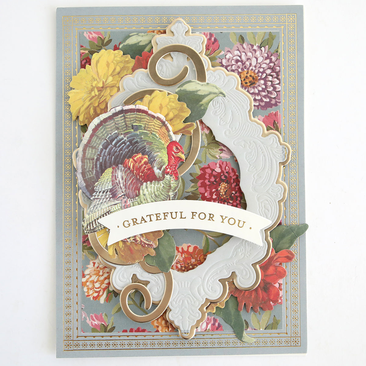 The Fall Ephemera Embellishments set includes a vibrant greeting card featuring a colorful turkey illustration, floral background, ornate white and gold frame, and a “Grateful For You” banner. Ideal for autumn scrapbooking, this set offers charming Thanksgiving touches to enhance your heartfelt creations.