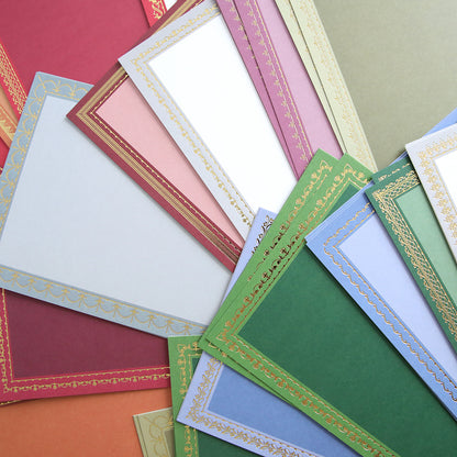 A selection of decorative sheets from the Holiday Photo Mat and Card Layer Bundle, featuring vibrant colors accented with gold-patterned borders, are fanned out on a flat surface—ideal for card making or adding a unique touch as a photo mat card layer.