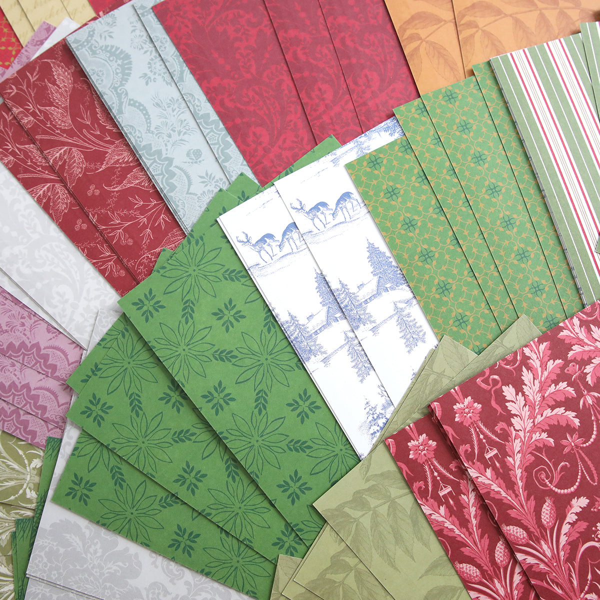 The Holiday Photo Mat and Card Layer Bundle showcases an array of patterned papers in red, green, white, and beige hues with floral, geometric, and scenic designs—ideal for card making or crafting distinctive seasonal photo mats.