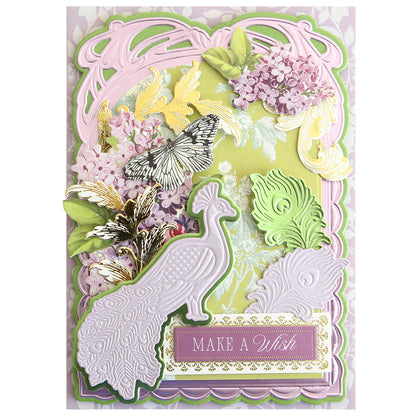 Beautifully crafted with the Peacock Scene 3D Dies, this greeting card showcases layered designs featuring a dimensional peacock, butterfly accents, gold birds, lilac flowers, and ornate patterns—all assembled using embossing dies and a layered die set—finished with a “MAKE A WISH” label at the bottom.