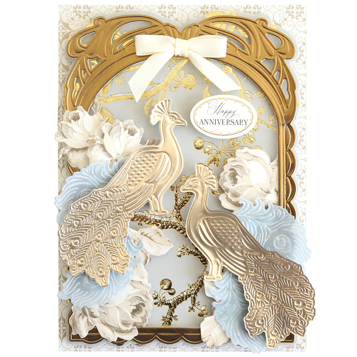 Greeting card featuring gold and cream peacocks crafted with the Peacock Scene 3D Dies, embellished with white roses, a gold ornate frame, a cream bow, and finished with an oval “Happy Anniversary” label.