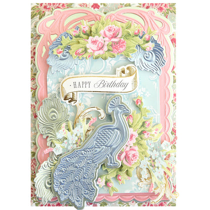 Celebrate a birthday with an ornate card featuring a blue peacock, pink roses, green leaves, and a “Happy Birthday” banner on a pastel decorative background—beautifully crafted using the Peacock Scene 3D Dies layered die set with delicate embossing dies for stunning dimension.