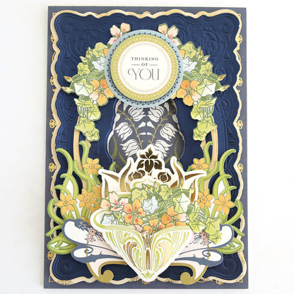 Handmade card with layered blue and gold borders, intricate floral designs, and a circular “Thinking of You” message at the top center—a beautiful addition to your scrapbook pages or any handmade cards collection crafted using your Dahlia Ultimate Papercrafting Collection.