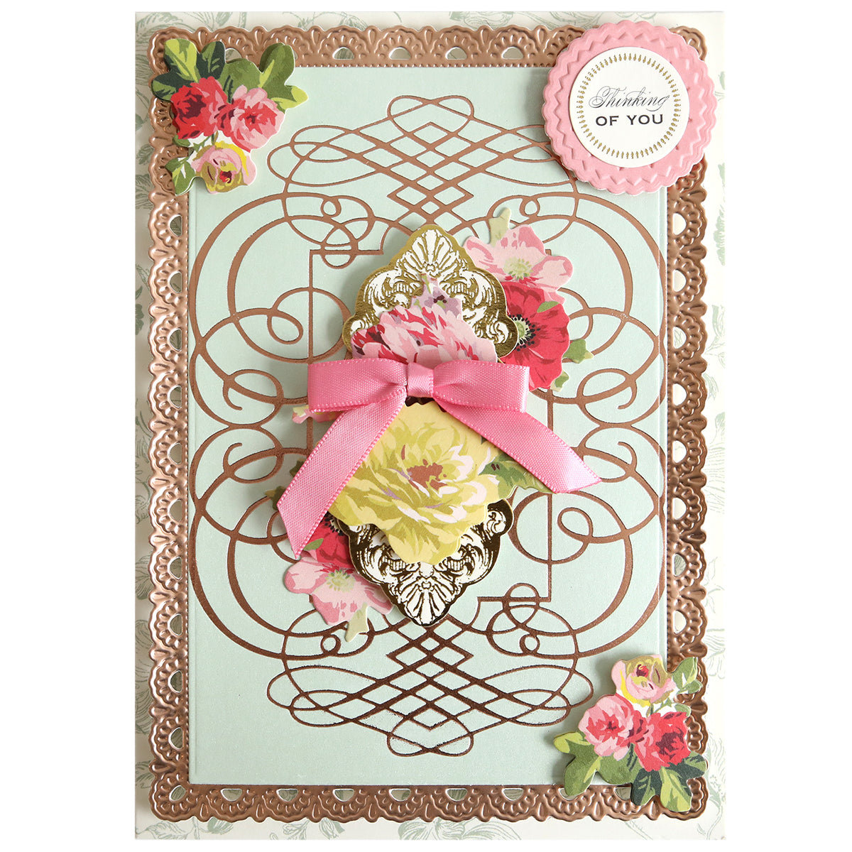 A decorative greeting card featuring elegant floral designs, intricate gold accents created with the Calligraphy Frame Gilded Hot Foil Plate, a pink ribbon embellishment, and a round “Thinking of You” label positioned in the top right corner.