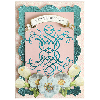 A birthday card featuring ornate blue and pink designs, accented with white flowers along the bottom and a “Happy Birthday To You” banner at the top—perfect for paper crafting enthusiasts. The elegant finish of this card is inspired by Flourish and Vine Gilded Hot Foil Plates, adding refined Empress Gild detailing reminiscent of luxurious hot foiling.