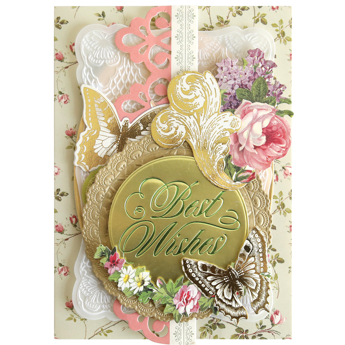 A handmade card featuring a Thoughtful Calligraphy Gilded Hot Foil Plates medallion embossed with “Best Wishes,” surrounded by paper cutouts of butterflies, flowers, and scrollwork on a floral background.
