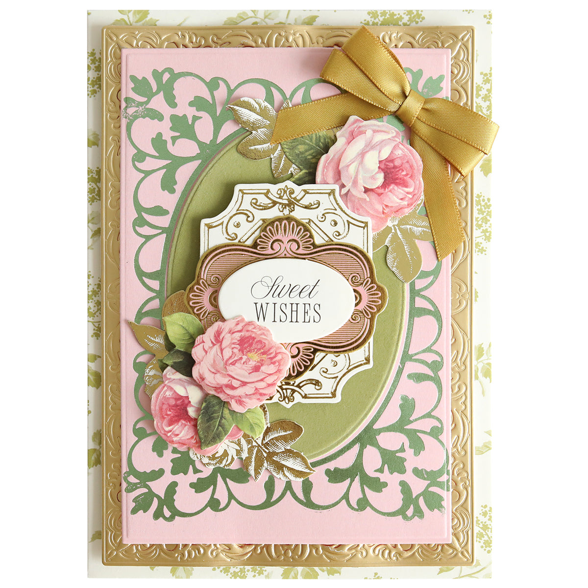 A decorative handmade card featuring gold, pink, and green floral designs with an elegant frame created using the Oval Flourish Frame Gilded Hot Foil Plate, finished with a gold ribbon bow and the words “Sweet Wishes” in the center surrounded by roses.