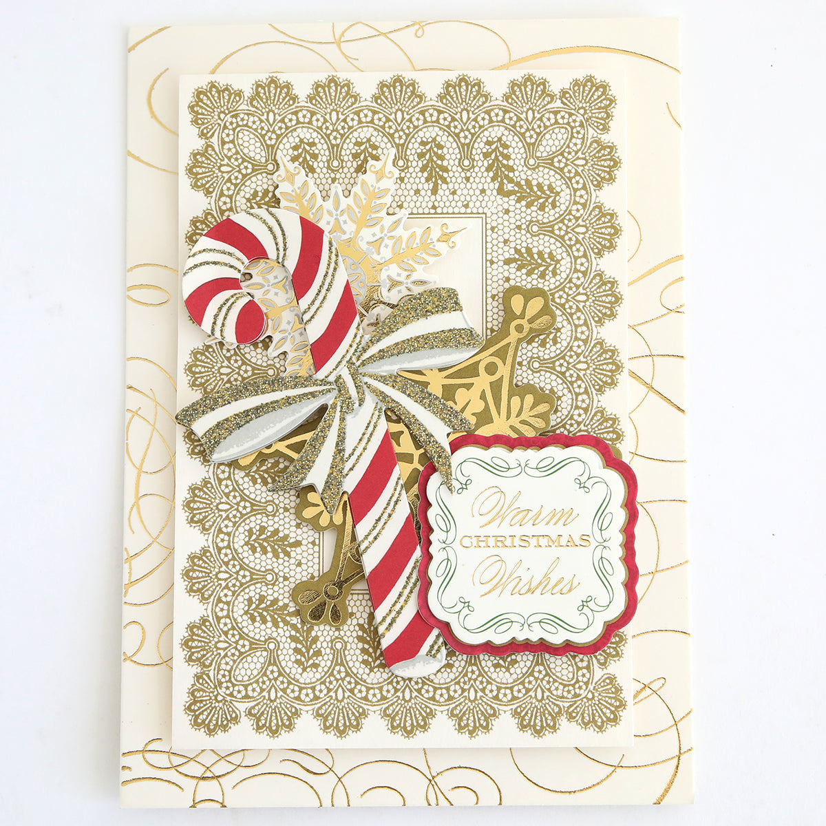 A decorative Christmas card adorned with Favorite Christmas Sentiment Stickers, featuring a gold lace pattern, a striped candy cane, gold snowflake, and a tag that reads “Warm Christmas Wishes.”.