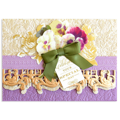 A decorative card made with Opulent Border Cut and Emboss Dies, featuring embossed motifs, purple and beige borders, floral designs, a green bow, embellishments, and a "Celebrate Your Special Day" tag.