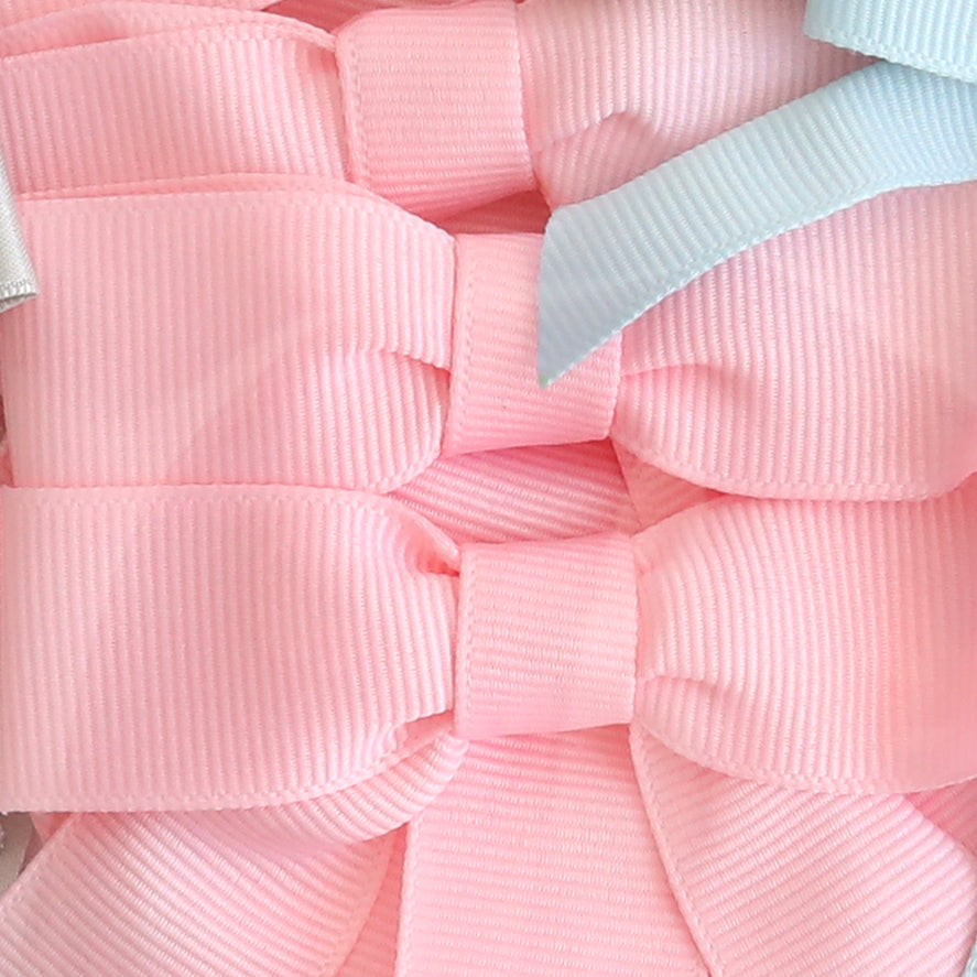 Close-up of several pink Pre-Tied Bows with Tails made from ribbed ribbon, with a partial light blue bow visible in the top right corner.