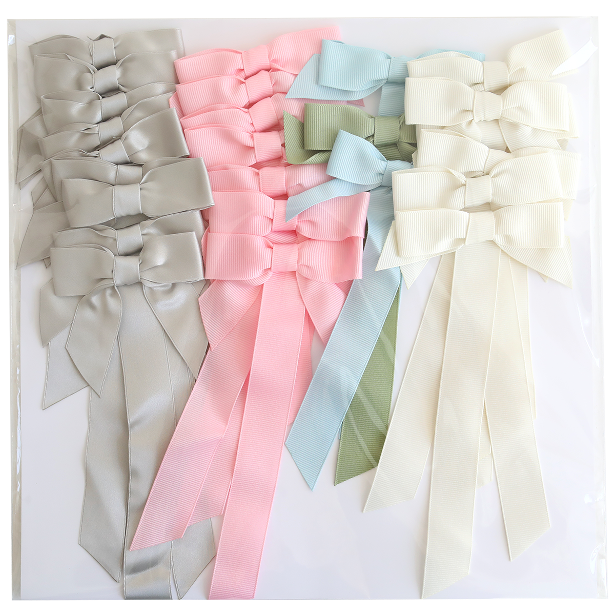 Seven large Pre-Tied Bows with Tails in light gray, pink, platinum, light green, light blue, and cream are arranged on a white surface.