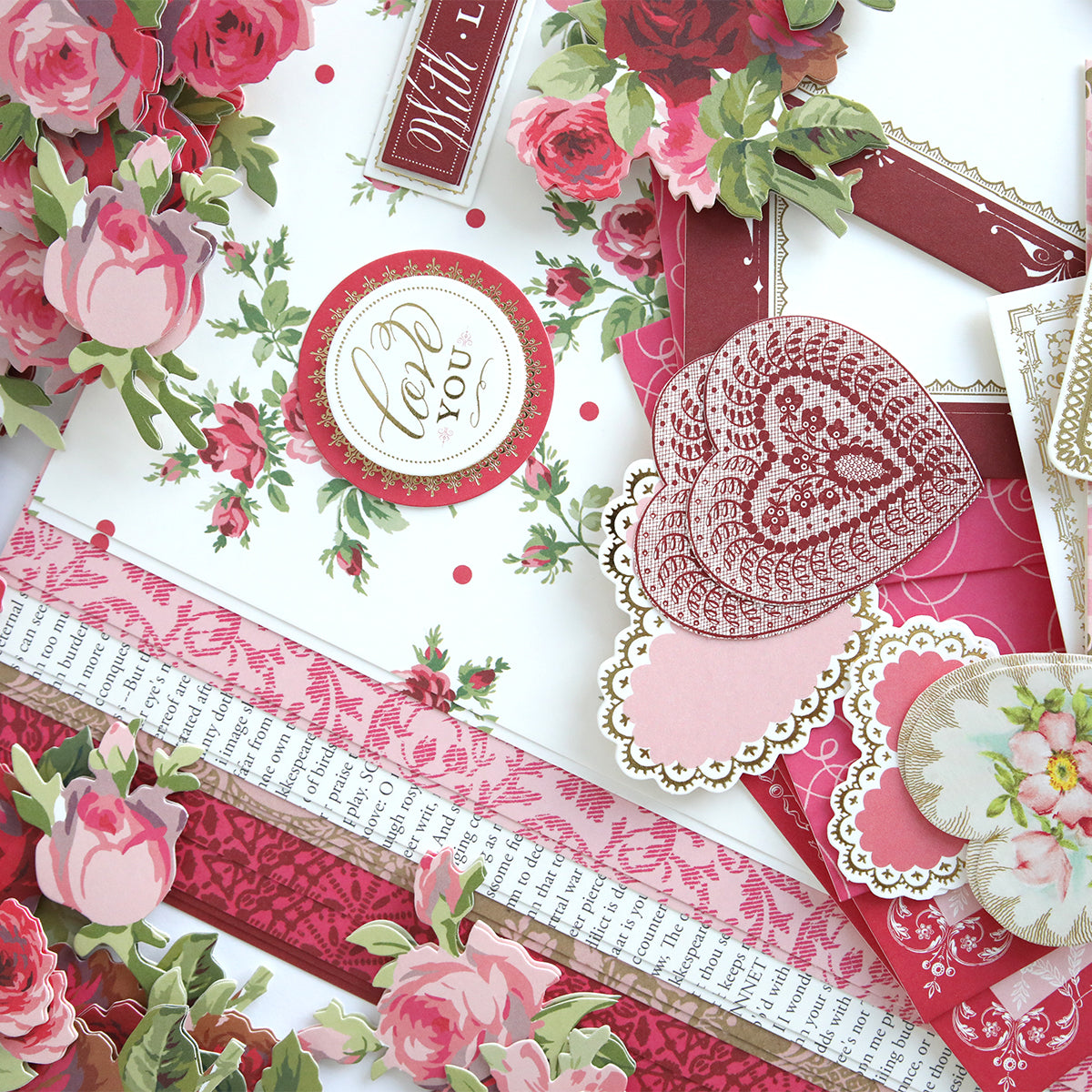 The Anna Griffin® 2026 Papercrafting Mystery Box Subscription offers assorted floral, heart, and lace decorative paper and embellishments in red, pink, and white—perfect for card making and papercrafting supplies.