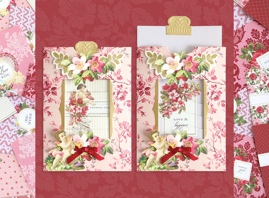 Two ornate pink floral greeting cards decorated with cherubs, flowers, and red bows are displayed on a matching red patterned background.