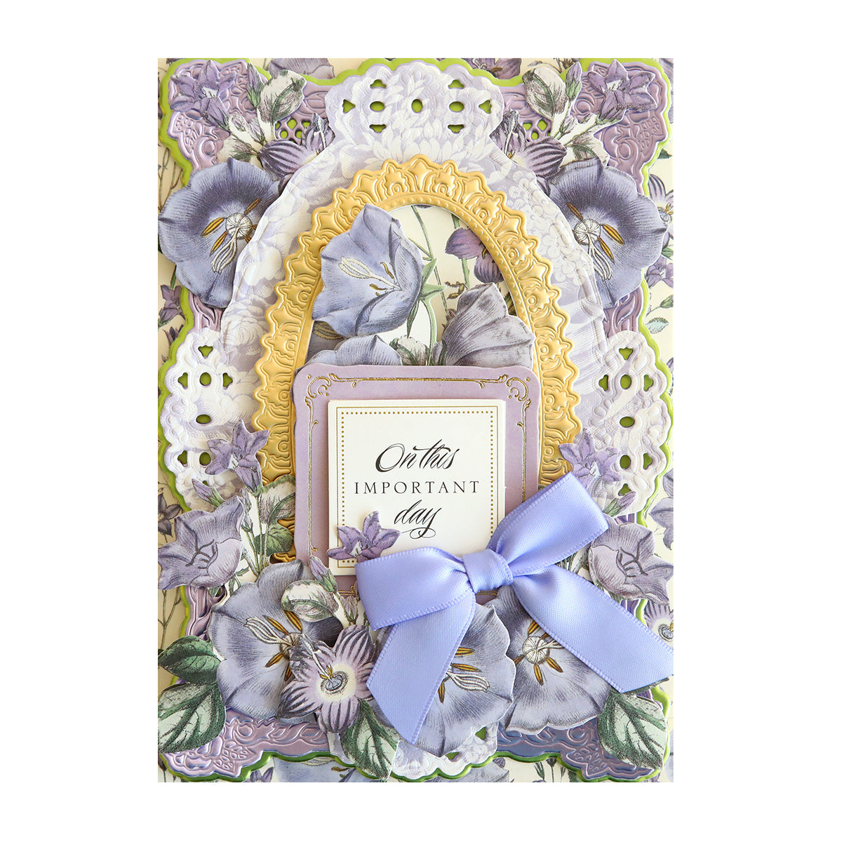 Anna's first designs include a card with purple flowers and a bow from the Anniversary Paper Crafting Collection, perfect for floral scrapbooking.
