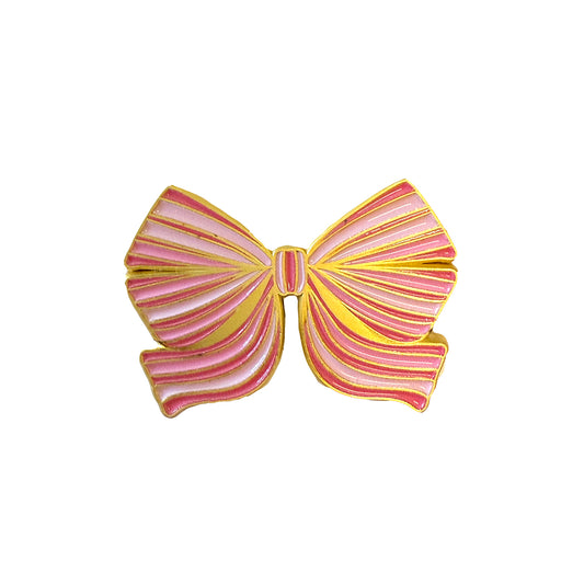 The Members Only August Pin is a pink and gold striped bow-shaped brooch with a shiny metallic finish from the 2025 Exclusive Pins collection—free with purchase. Shown on a white background.