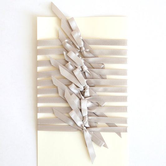 A handmade card is elegantly decorated with multiple silver satin bows from the Silver Satin Bows 10 count set, each pre-tied and arranged in a stylish horizontal pattern.