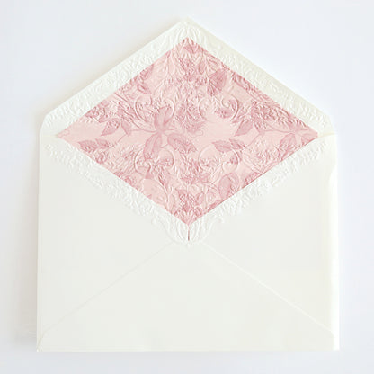 A white envelope with an intricate floral pattern lining in pastel pink is open, revealing the decorative interior of the Birthday Greetings Envelope Liners, perfect for complementing handmade cards.