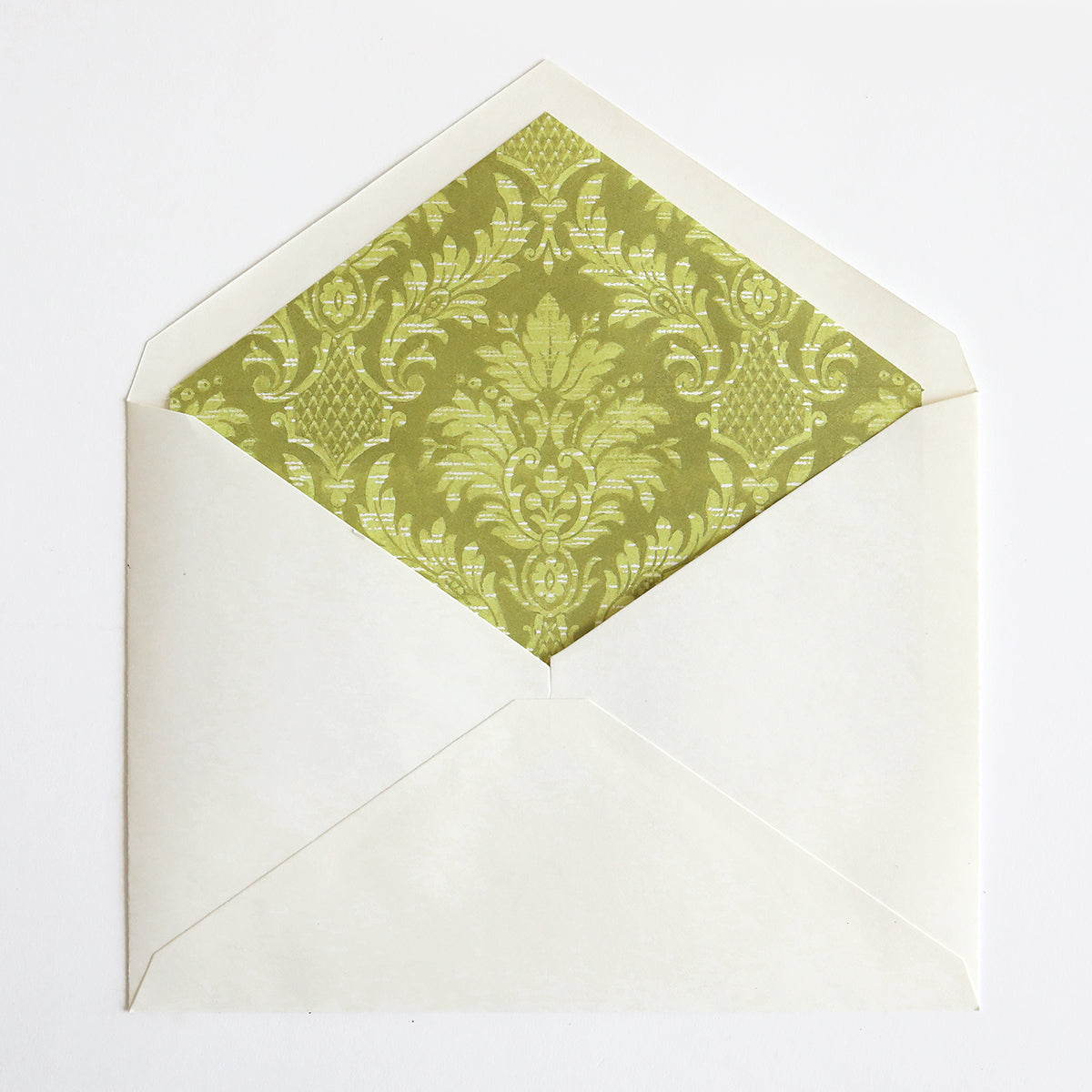 A white envelope partially open reveals a green and gold ornate patterned interior, featuring luxurious foil accents, known as Birthday Greetings Envelope Liners.