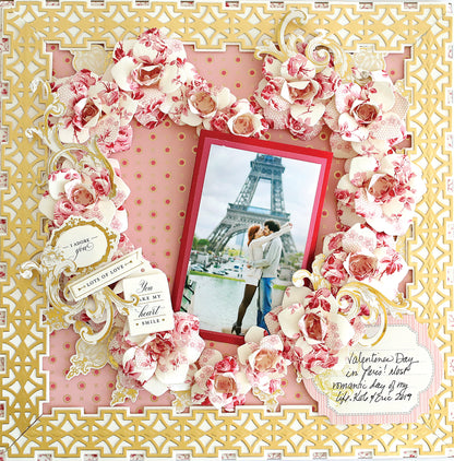 A decorative scrapbook page featuring a central photo of a couple kissing in front of the Eiffel Tower, surrounded by ornate floral and lace designs, with a Valentine's Day theme, perfect for showcasing your Crop at Home II Swag.