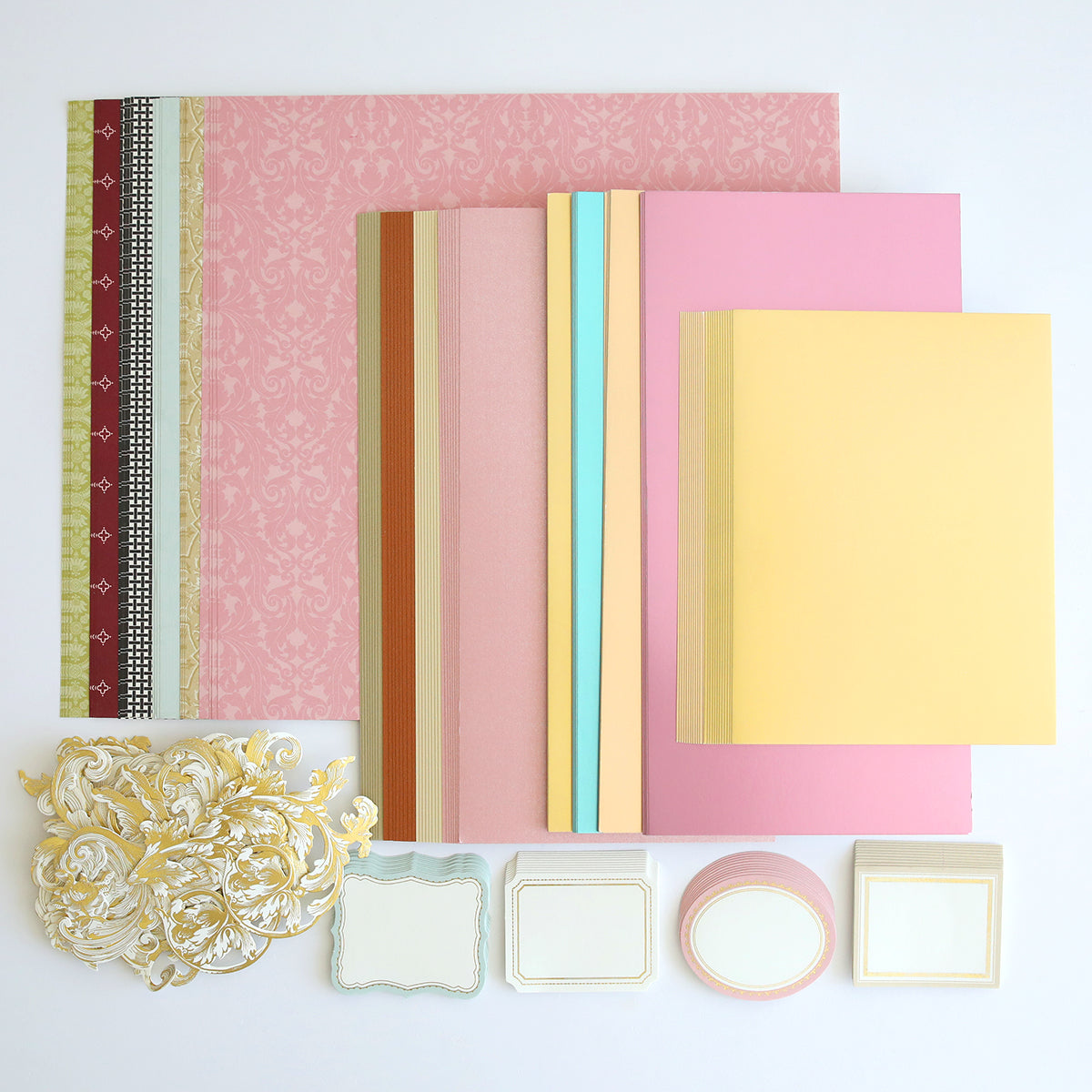 A collection of decorative paper, cutouts, and blank labels in various colors and designs, perfect for scrapbooking or cardmaking projects. Highlights include pink, yellow, and multicolored striped patterns that will add a touch of creativity to your crafts. Crop at Home II Swag.