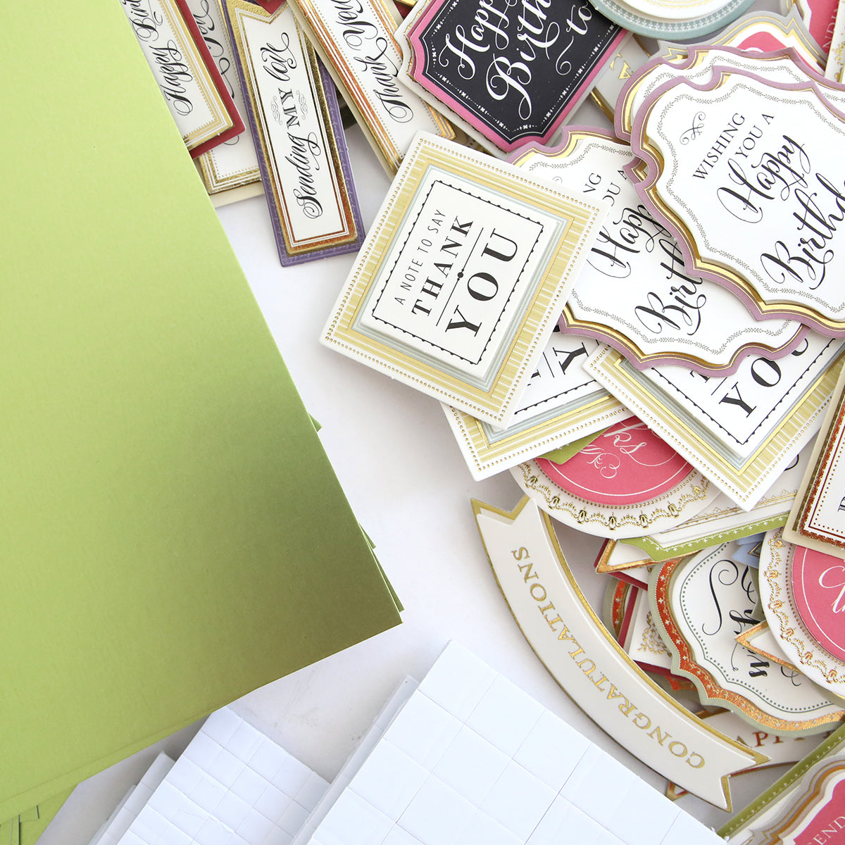 The Create Supply Box includes green envelopes and assorted decorative greeting card tags with celebratory messages, featuring 3D Sentiment Stickers and Matte Foil Cardstock for crafting elegant event supplies.