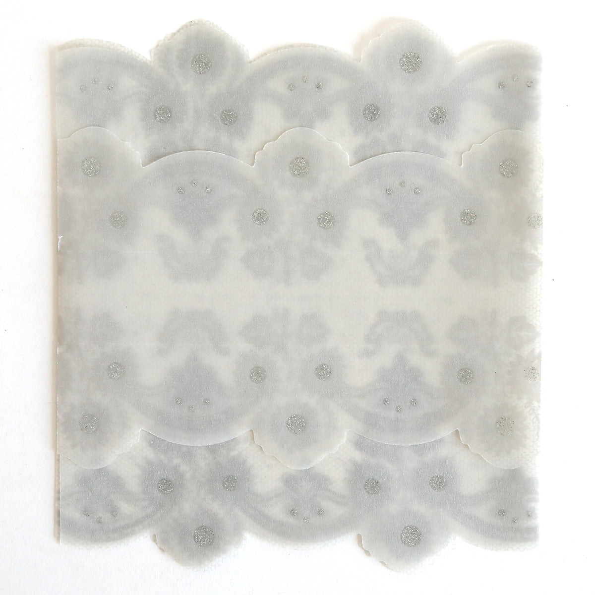 The Silver Vellum Gatefold Wrap 10 pack features translucent, scalloped-edged paper with a symmetrical decorative pattern and dotted details, ideal for creating elegant wedding invitation or lace vellum wraps.