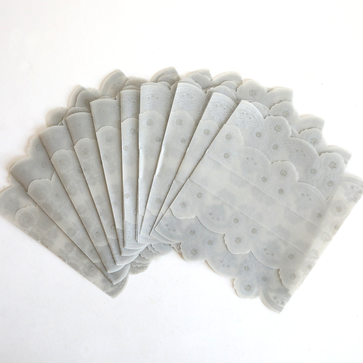 Ten silver vellum gatefold wraps with scalloped edges are fanned out on a white surface, ideal for elegantly presenting invitations. Available as a 10 pack.