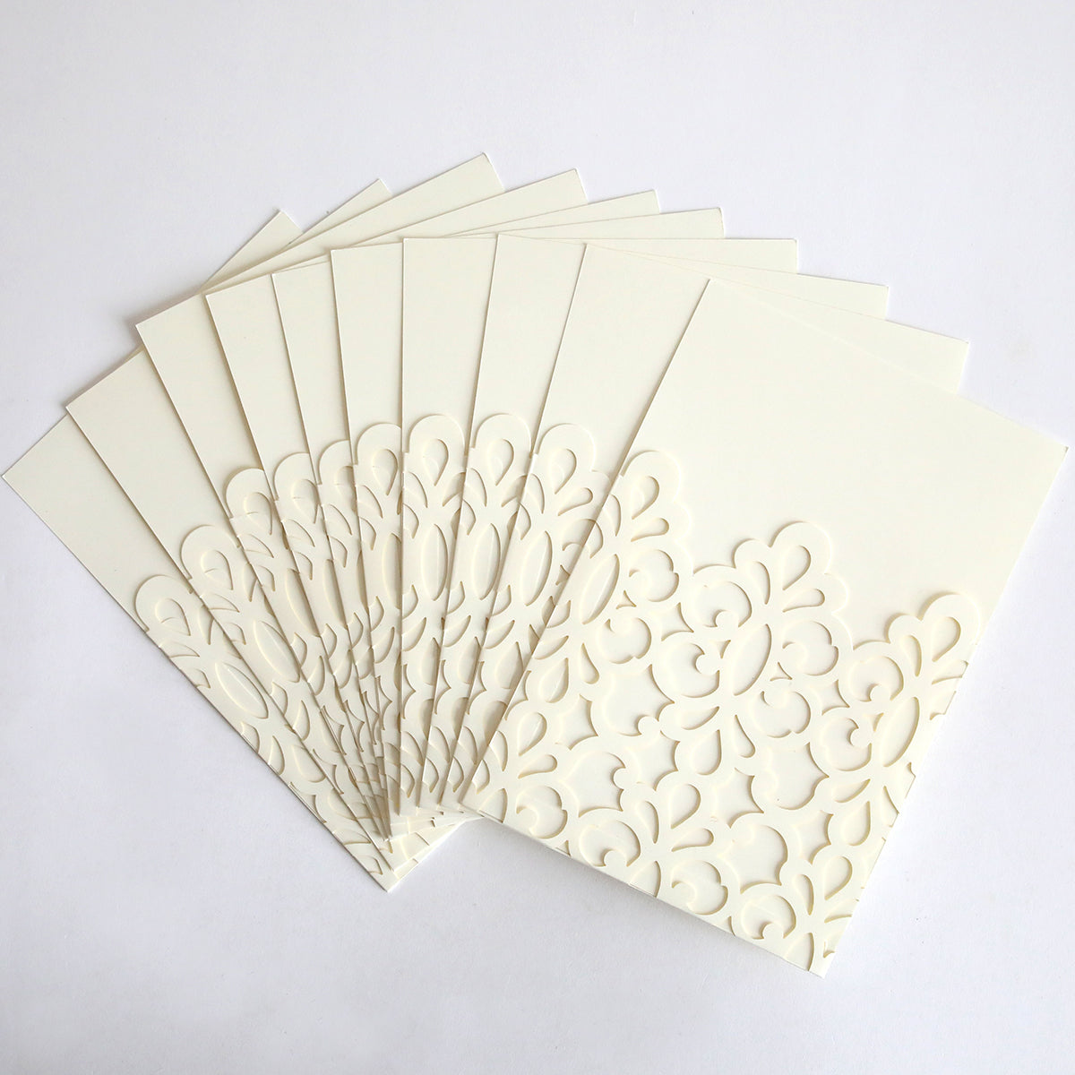 The Ivory Medallion Diecut Pocket 10 pack features elegant cream-colored cards with intricate floral cut-out designs and white diecut medallion pockets, beautifully arranged in a fan shape on a white background.