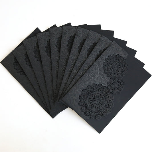 The Black Laser Cut Lace Pocket 10 pack features intricately patterned black pockets, perfect for elegant wedding invitations, all set against a white background.