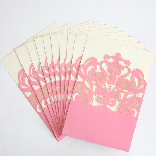 A fanned-out stack of Pink Laser Cut Pocket 10 pack wedding invitations in cream, each featuring intricate pink lace pockets, displayed on a white surface.