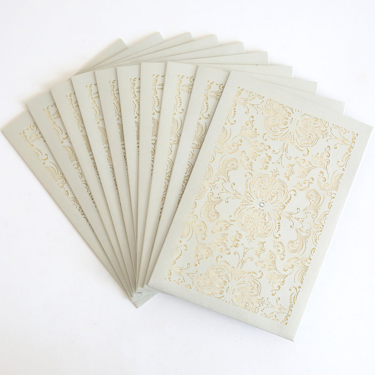 A set of Silver Intricate Sleeve 10 pack laser-cut invitation sleeves arranged in a fan shape, each featuring an ornate decorative pattern on the front.