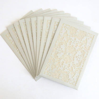 A set of Silver Intricate Sleeve 10 pack laser-cut invitation sleeves arranged in a fan shape, each featuring an ornate decorative pattern on the front.