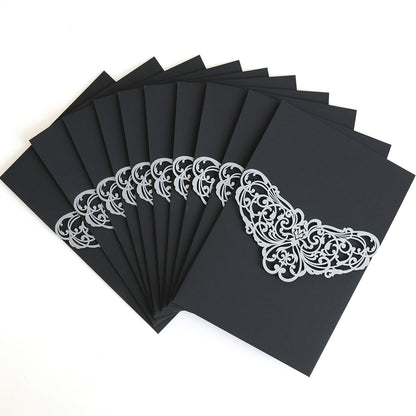 A set of Black Laser Foil Flap Pocket invitations (10 pack) is fanned out on a white surface, highlighting their elegant silver foil ornamental designs.