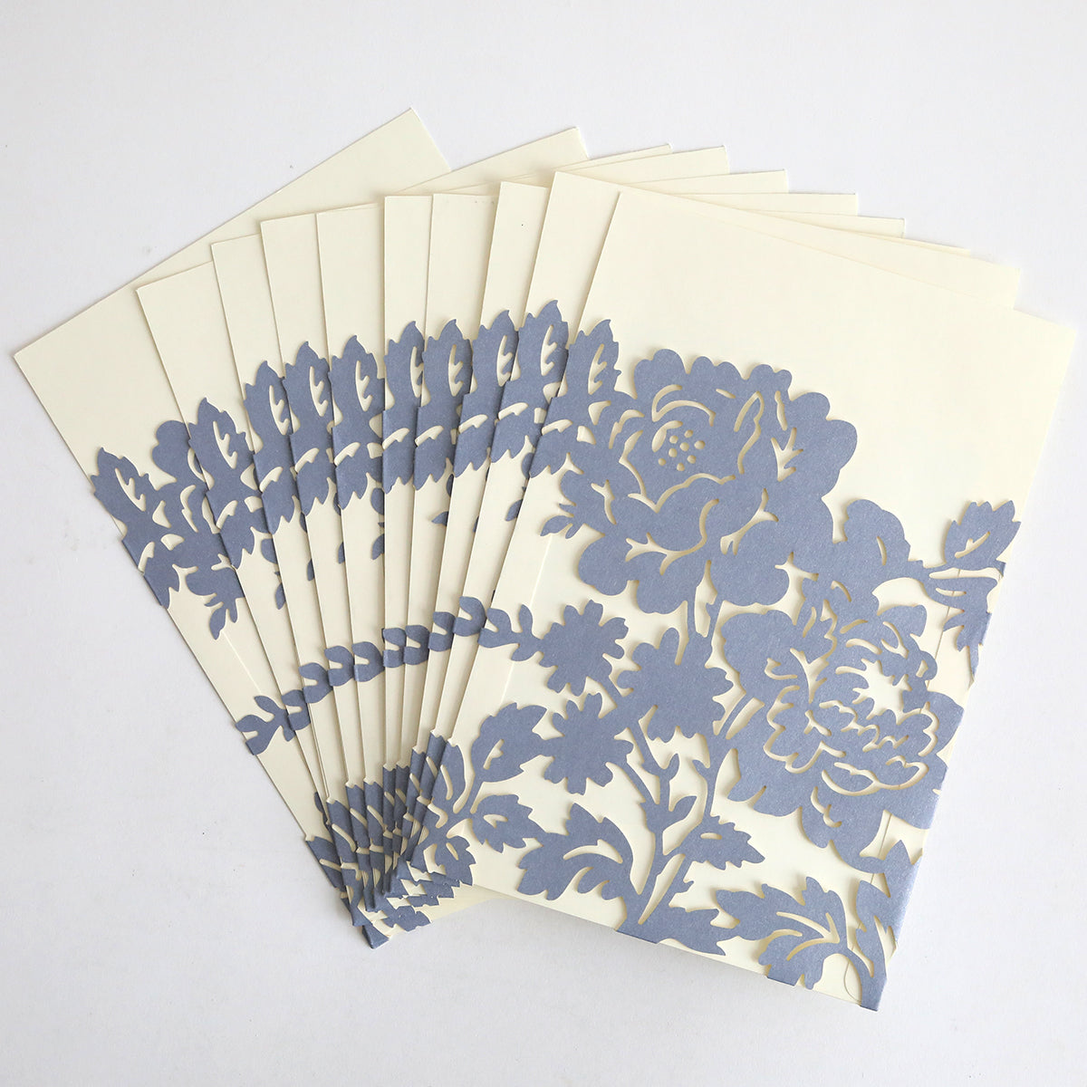 A set of Slate Blue Rose Diecut Pocket cards (10 pack) with cream inserts and intricate silver floral cutout designs is fanned out on a white surface.