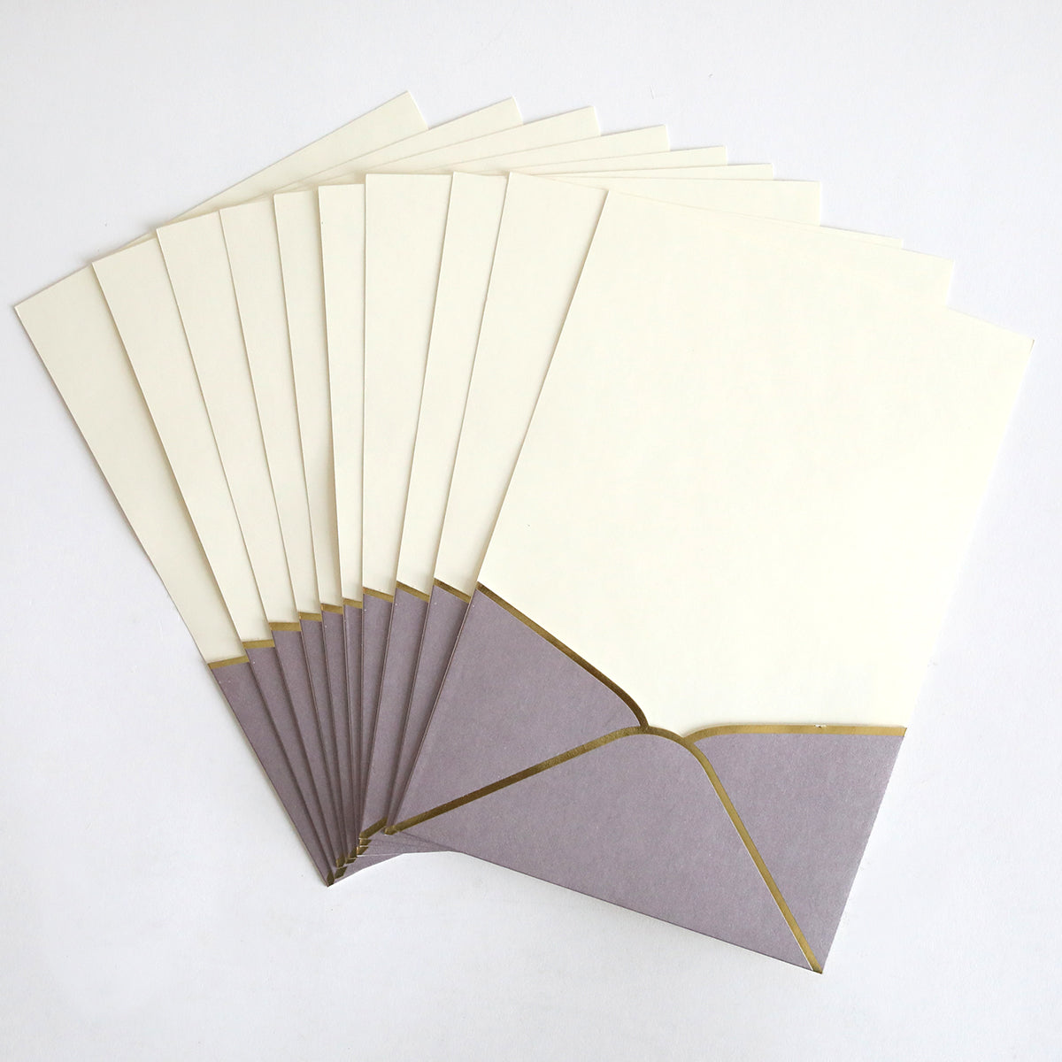 A 10-pack of Lavender Metallic Envelope Pockets with gold trim, each holding cream wedding invitations, displayed fanned out on a white background.
